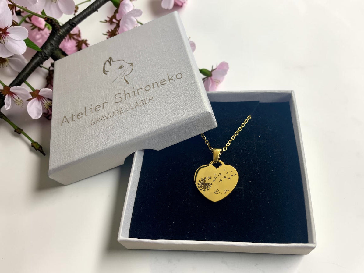 Collier cœur pissenlit doré présenté dans son écrin noir et blanc gravé Atelier Shironeko