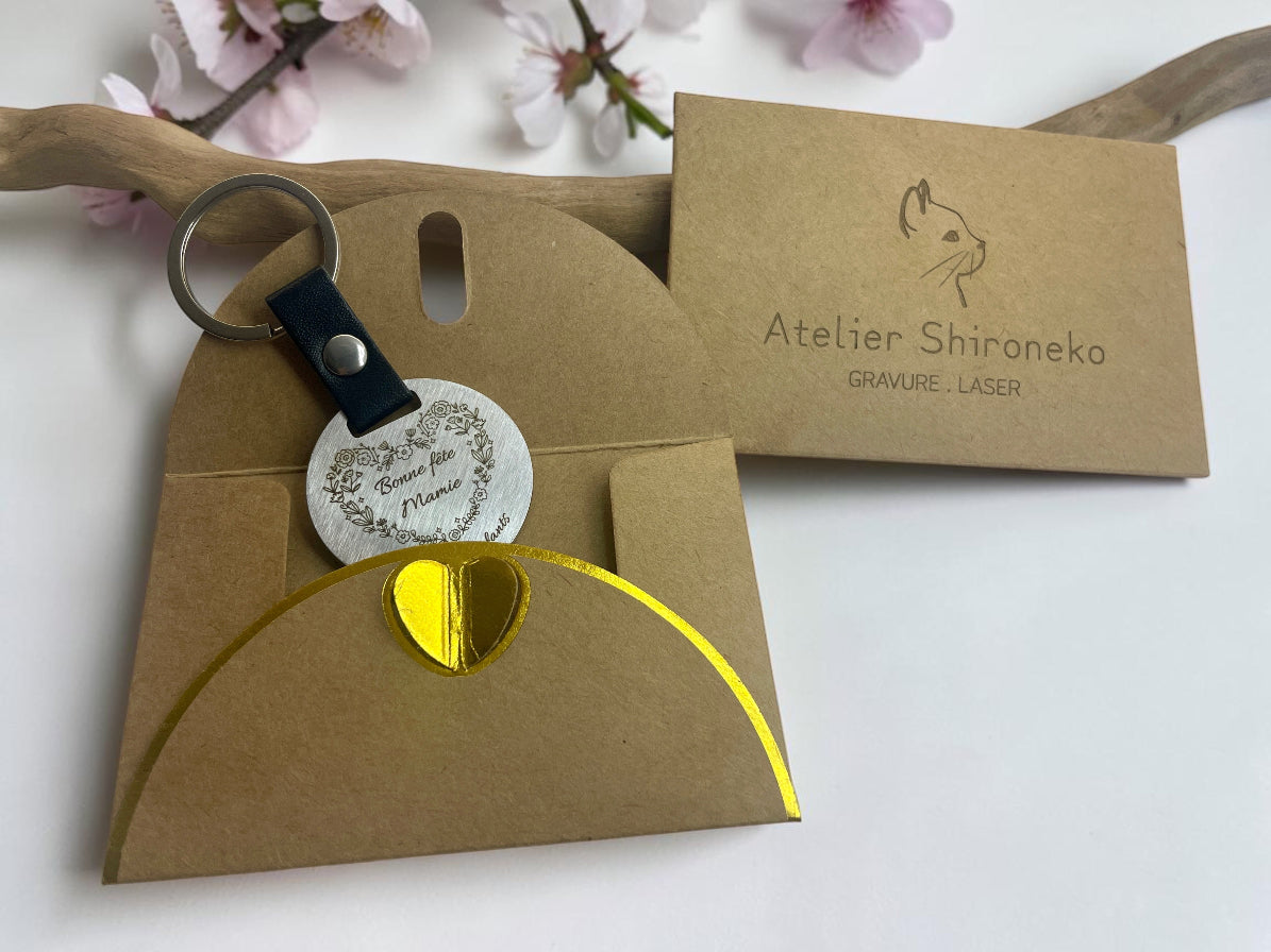 Porte-clés acier gravé Bonne fête Mamie, présenté dans sa pochette cadeau kraft Atelier Shironeko