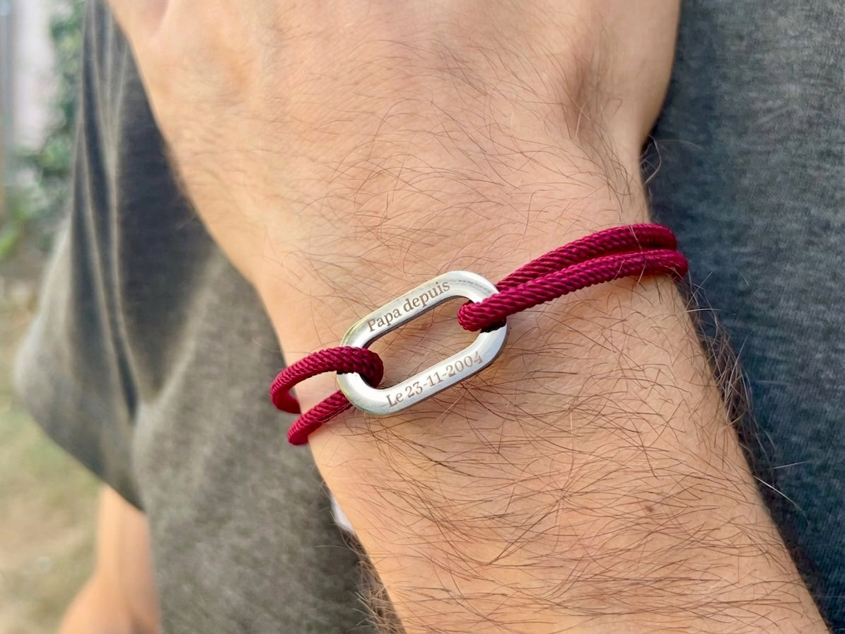 Bracelet cordon rouge à maillon acier porté au poignet d'un homme