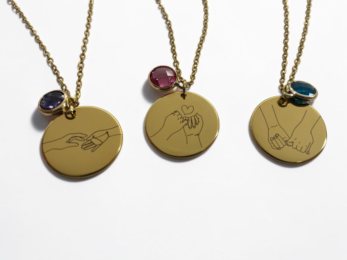 Trois colliers médaille dorée gravés de mains entrelacées, avec pierres de naissance