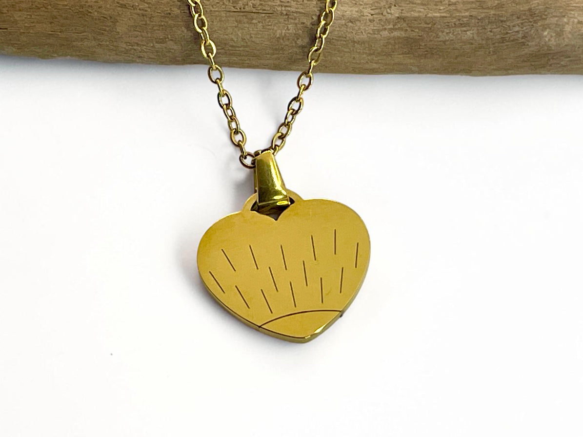 Collier cœur doré gravé d'un soleil, porté sur sa chaîne fine