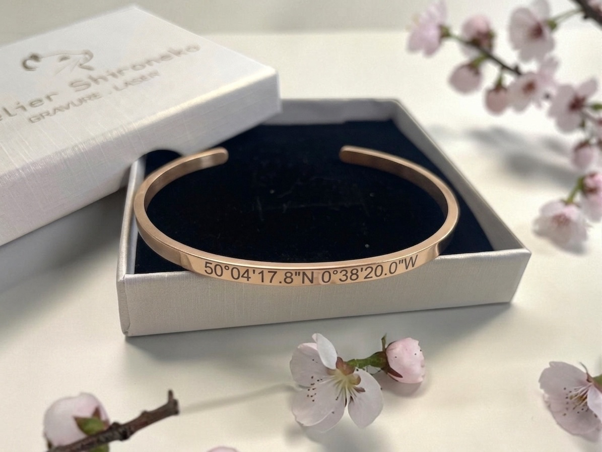 Bracelet jonc doré coordonnées GPS dans son écrin noir et blanc, décor de fleurs de cerisier