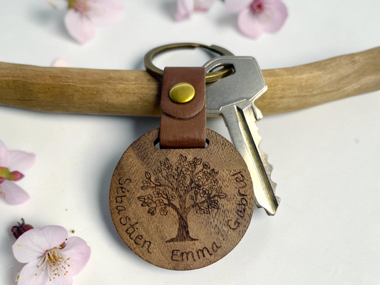 Porte-clés bois arbre de vie posé sur une branche fleurie de cerisier, avec une clé