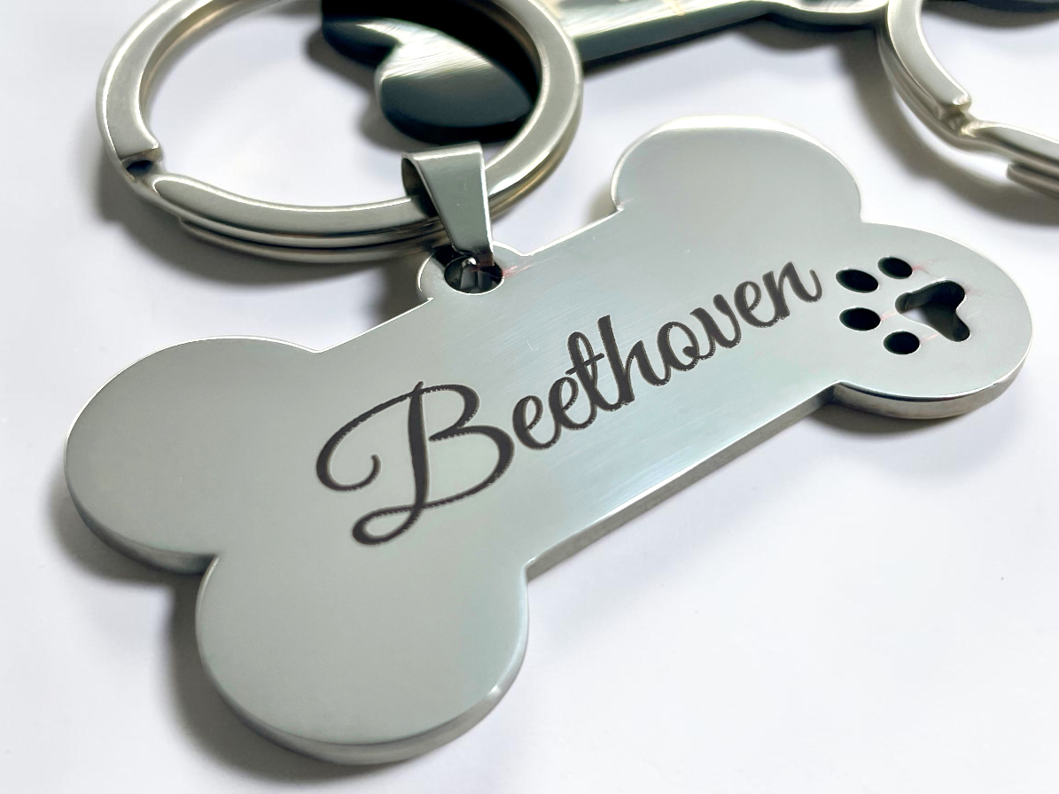 Gros plan de la gravure du prénom Beethoven et de l'empreinte de patte sur médaille acier
