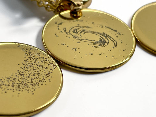 Gros plan de la gravure d'une galaxie spirale sur médaille dorée, motif voie lactée