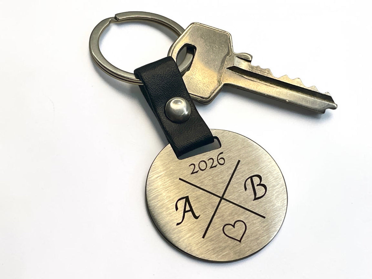 Porte-clés rond gravé initiales A et B avec anneau bronze, attaché à une clé de maison