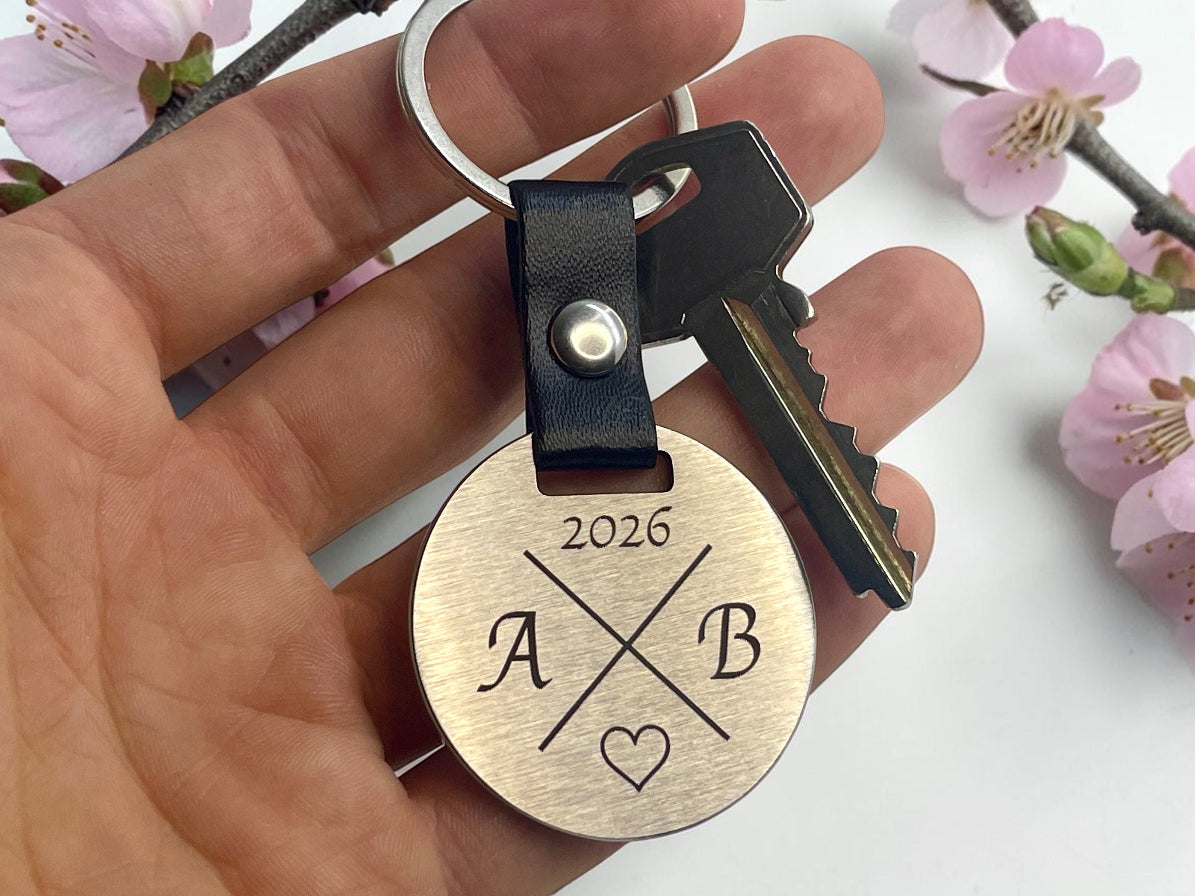 Porte-clés personnalisé initiales et date tenu en main, décor de fleurs de cerisier