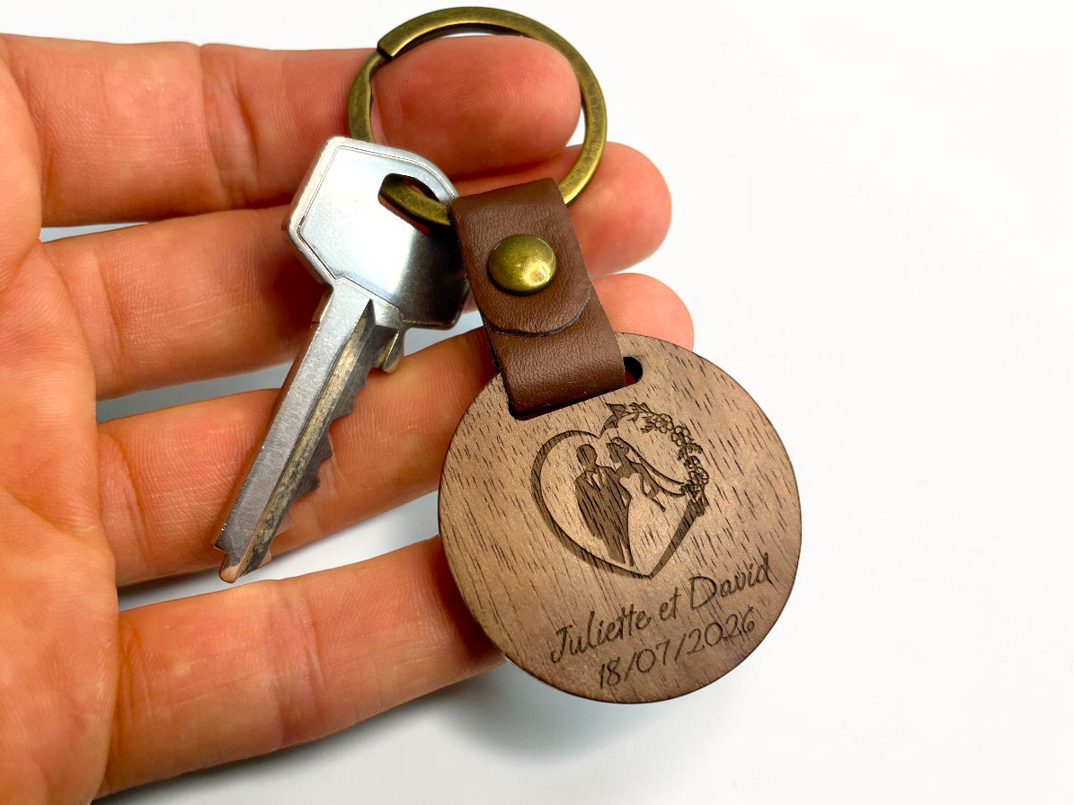 Porte-clés bois rond gravé prénoms des mariés, tenu en main avec une clé