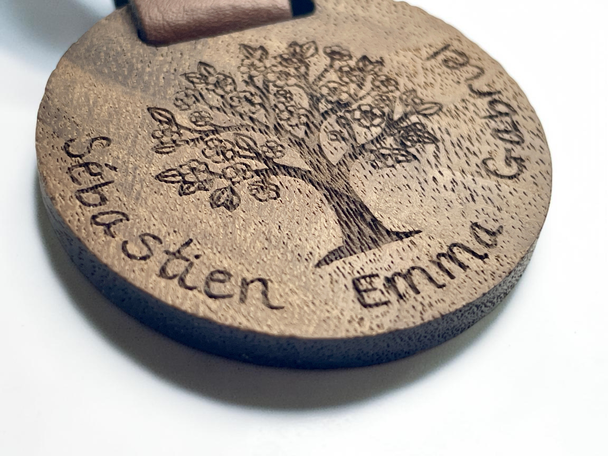 Gros plan de la gravure arbre de vie et des prénoms Sébastien, Emma et Gabriel autour du médaillon