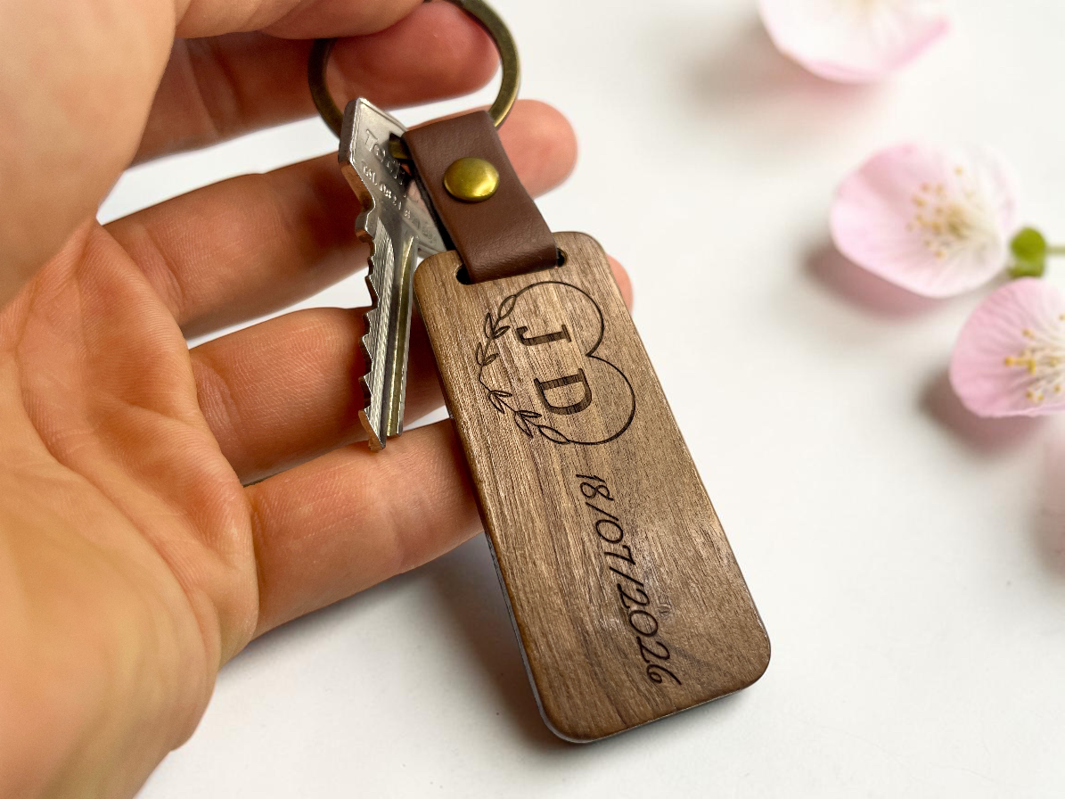Porte-clés bois gravés tenus en main, décor de fleurs de cerisier
