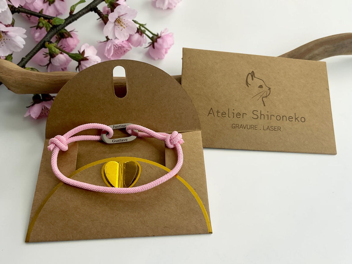 Bracelet cordon rose dans sa pochette cadeau kraft avec la carte Atelier Shironeko