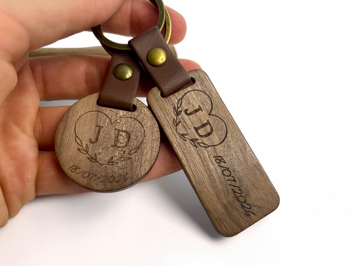 Deux porte-clés bois personnalisés tenus en main, modèles rond et rectangulaire