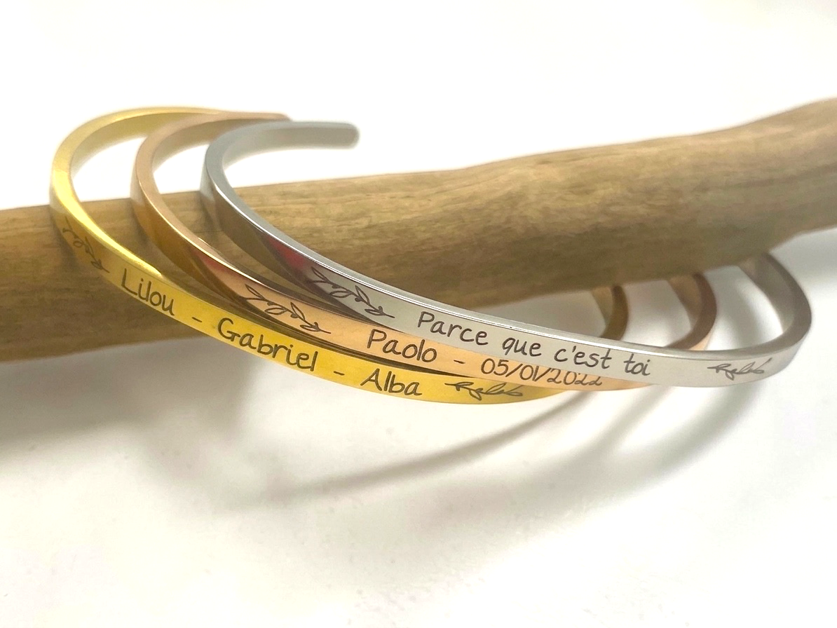 Trois bracelets joncs gravés superposés sur une branche, messages et prénoms personnalisés