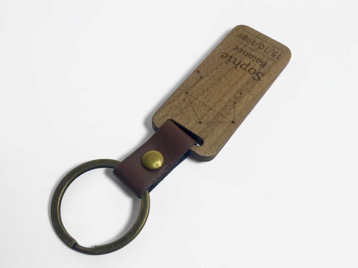 Porte-clés bois rectangulaire vu de trois quarts, lanière cuir marron et anneau bronze