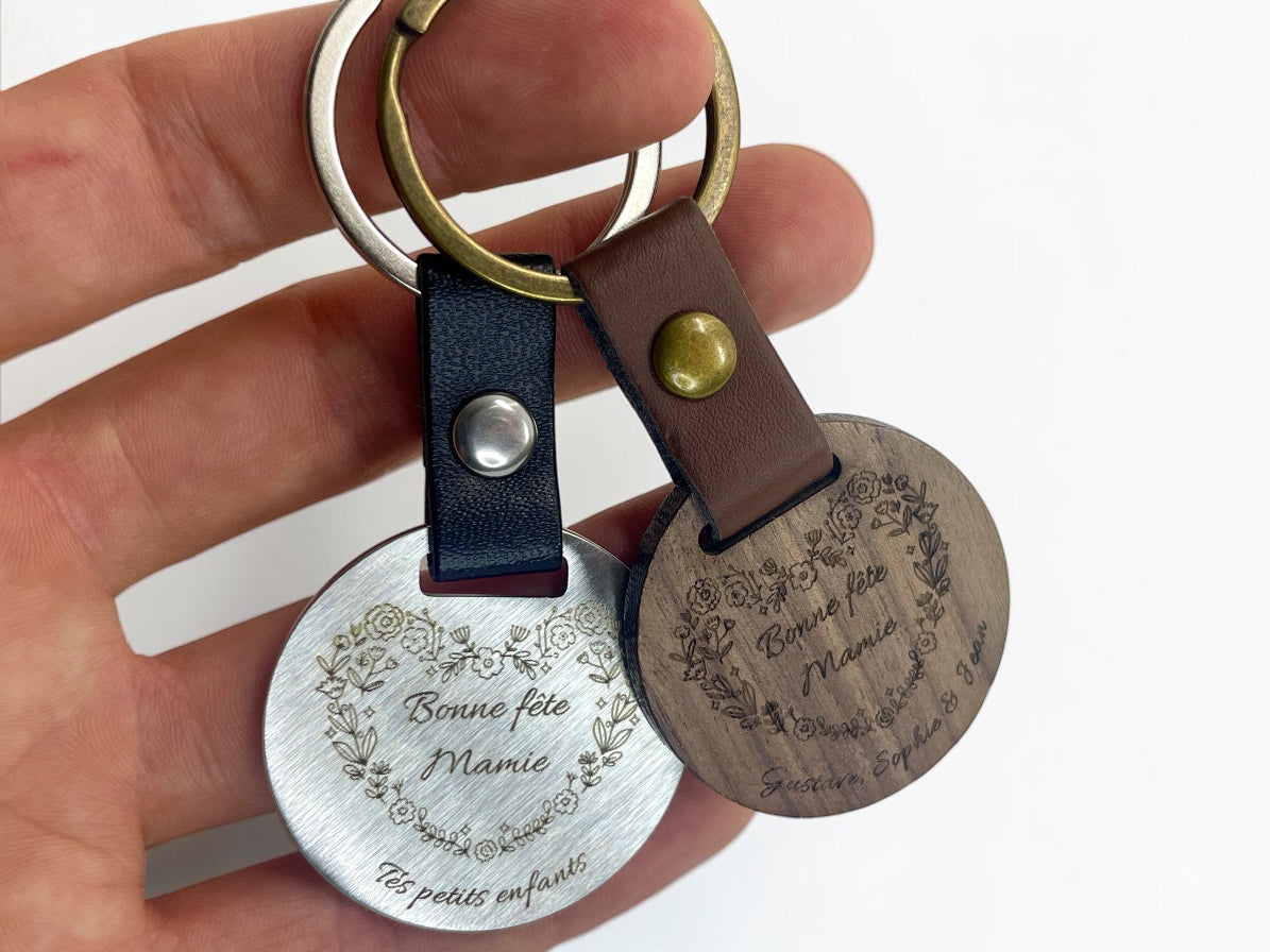 Deux porte-clés gravés Mamie tenus en main pour montrer leur taille réelle