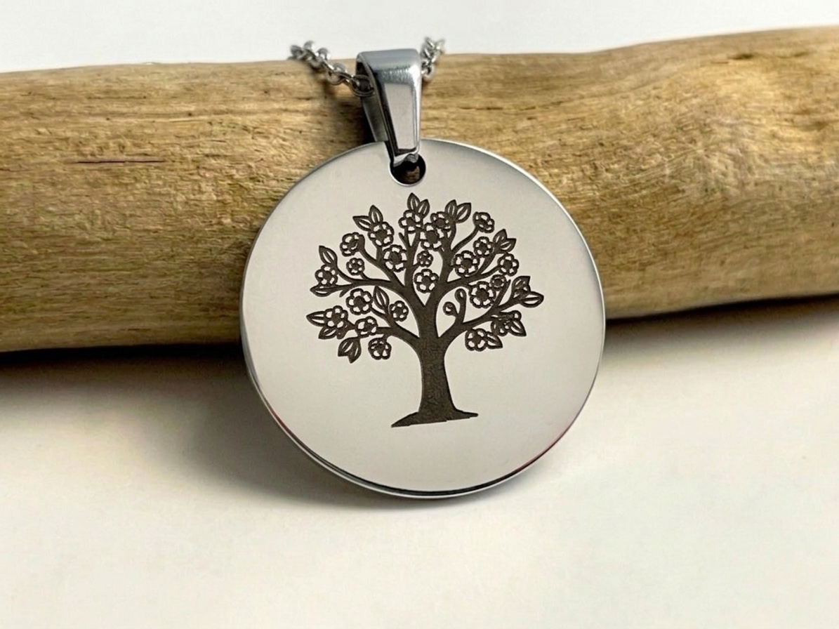 Collier médaille ronde argentée gravée d'un arbre de vie, suspendu à une branche de bois