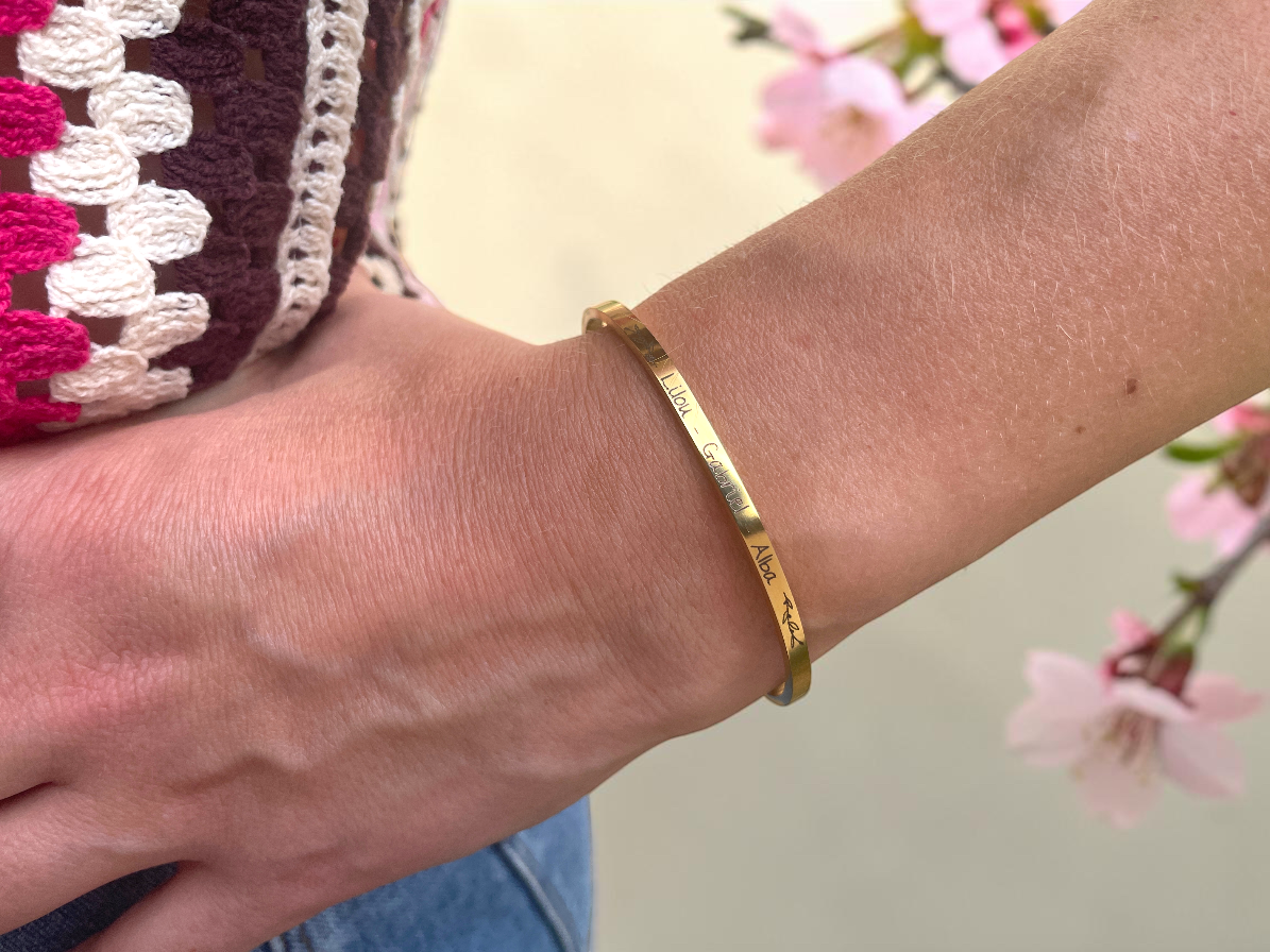 Bracelet jonc doré personnalisé porté au poignet, décor de fleurs de cerisier