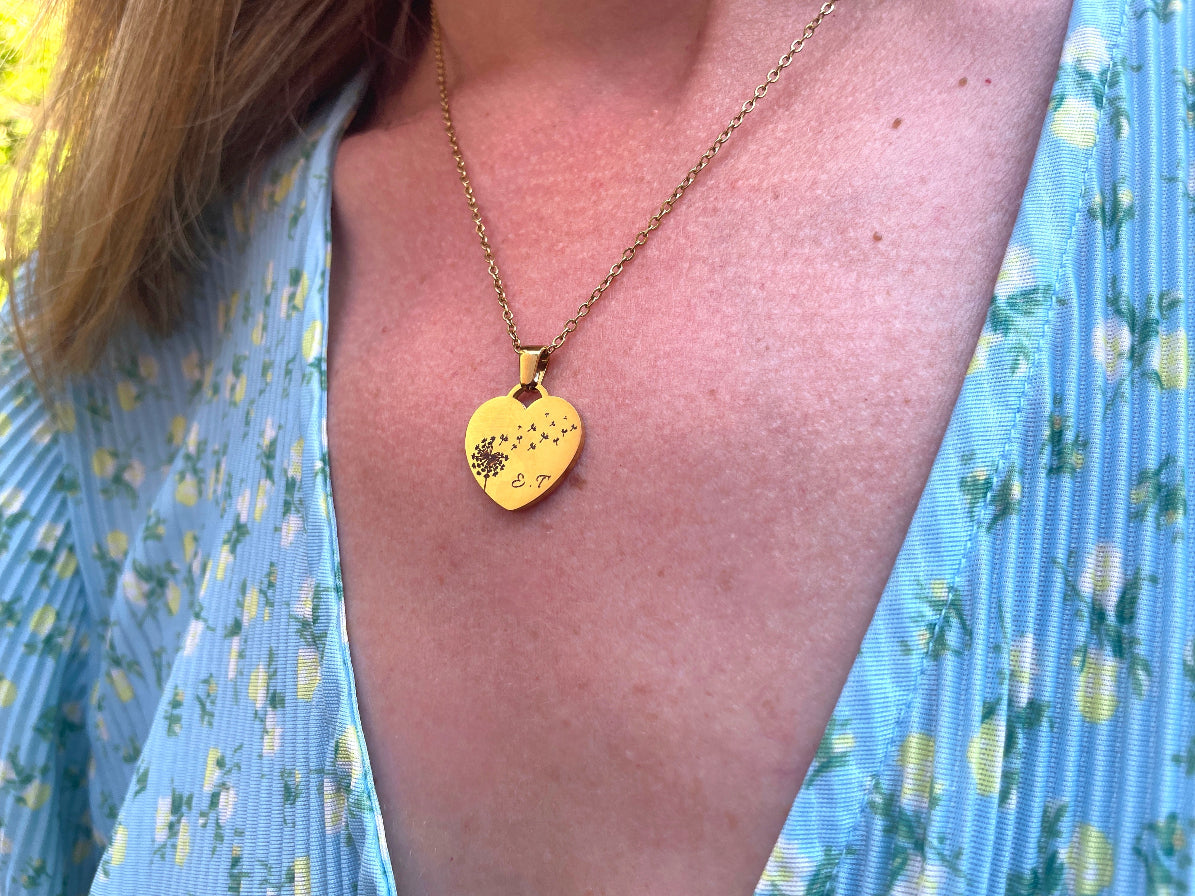 Collier cœur pissenlit doré porté au cou, sur un chemisier bleu clair