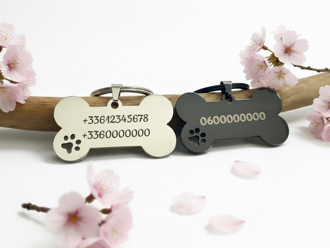 Deux médailles chien os gravées prénom et numéro, posées sur une branche fleurie de cerisier