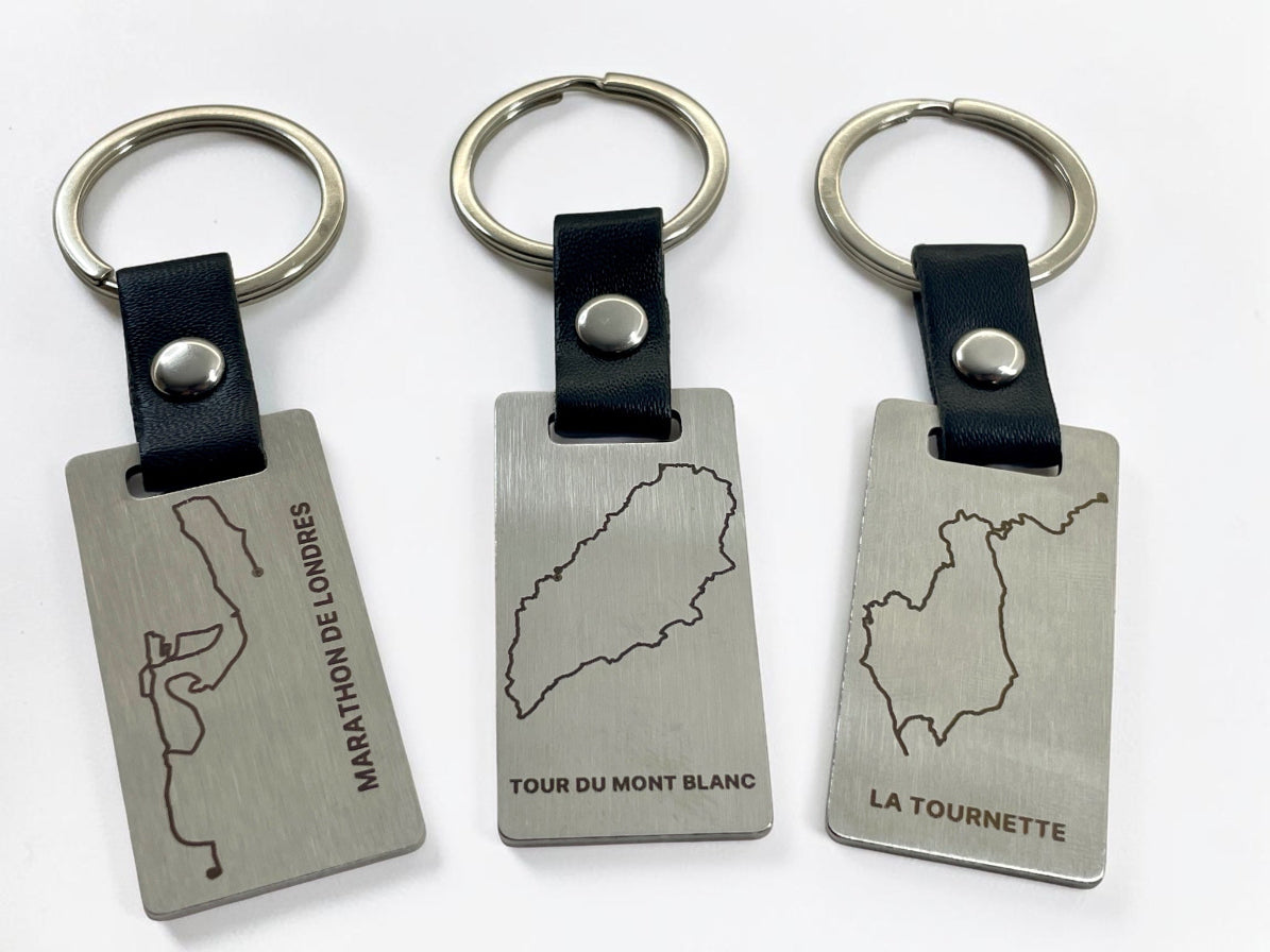 Trois porte-clés acier personnalisés gravés de tracés GPX différents, alignés côte à côte