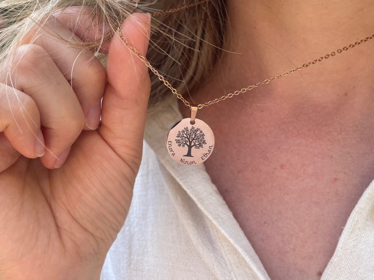Collier arbre de vie or rose porté au cou, tenu entre les doigts