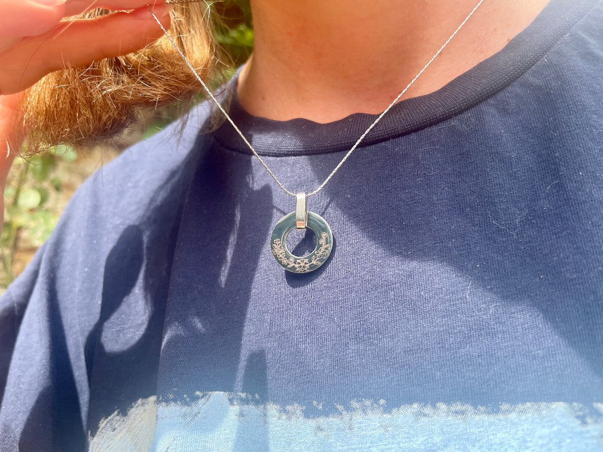 Collier médaille ajourée porté au cou, sur un haut bleu