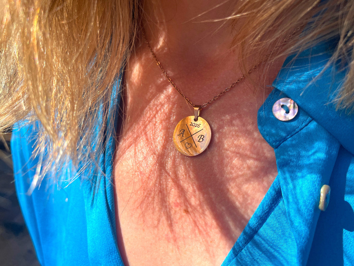 Collier médaille ronde doré porté au cou, sur une veste bleue