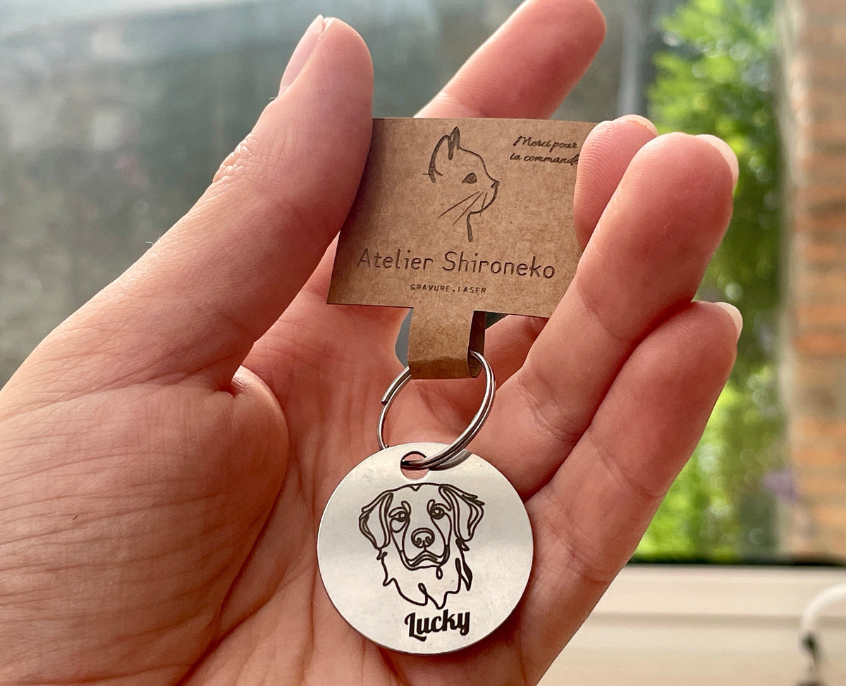 Médaille chien portrait de race tenue en main, gravée du prénom Lucky