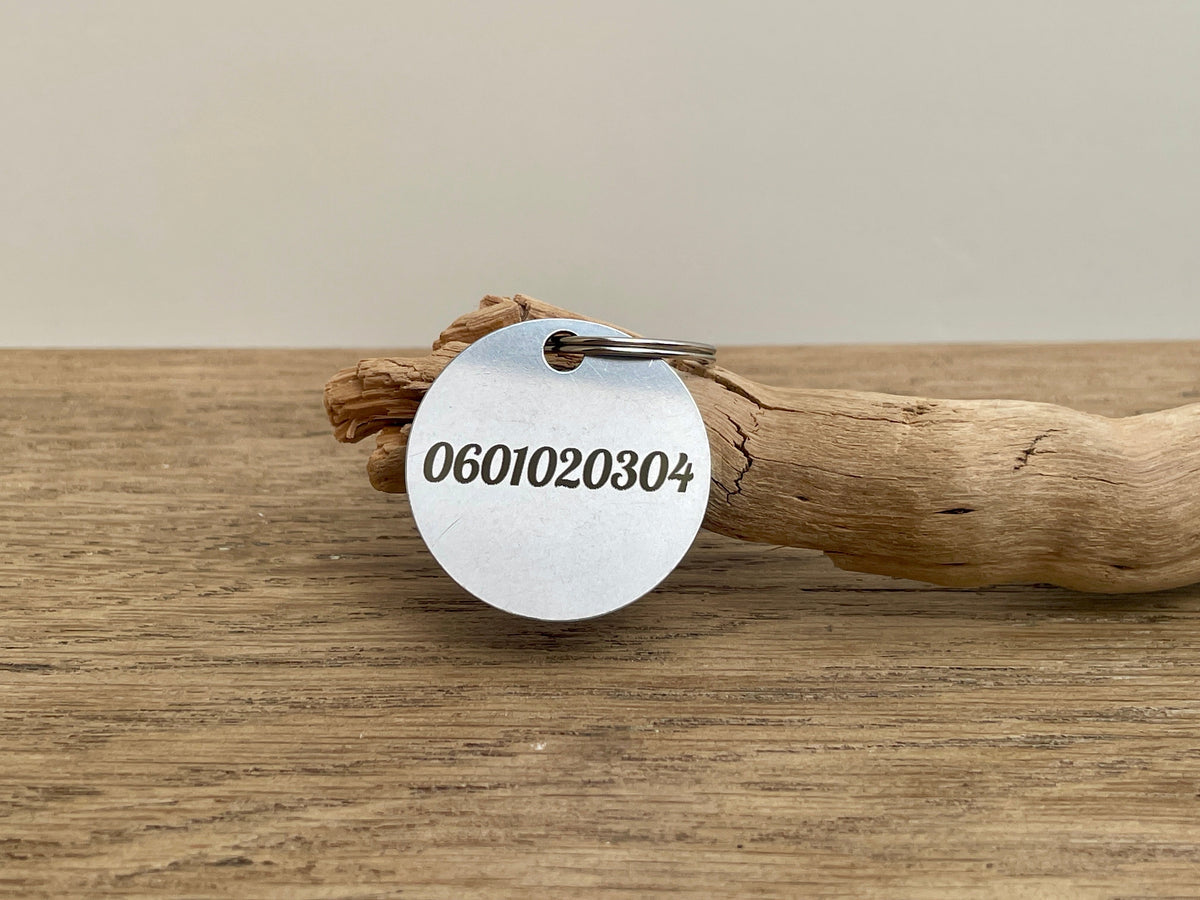 Verso d'une médaille chien ronde gravé du numéro de téléphone du propriétaire